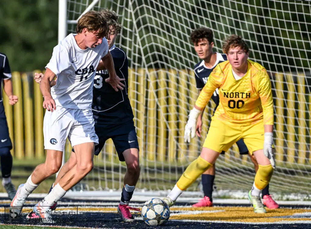 CBA Liam Wheeler - Shore Sports Insider CBA senior Liam Wheeler wards off Toms River North defender Vinny Orlando while goalkeeper Gavin Stryker (00) and Manuele Lubrano defende the net. (Photo: Tom Smith | tspsportsimages.com) - CBA Liam Wheeler