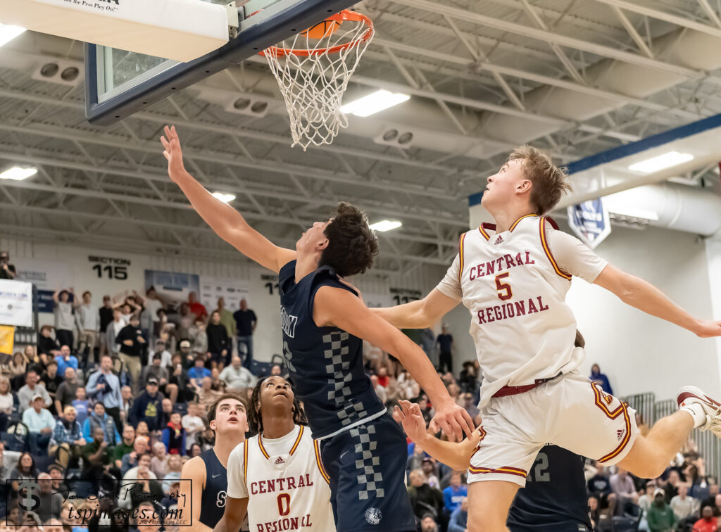 Manasquan sophomore Logan Cleveland lays in the winning shot between Central seniors Royalty Riley (0) and Aidan Graham (5) in the WOBM Christmas Classic Final. (Photo: Tom Smith | tspimages.com) - Manasquan vs. Central WOBM