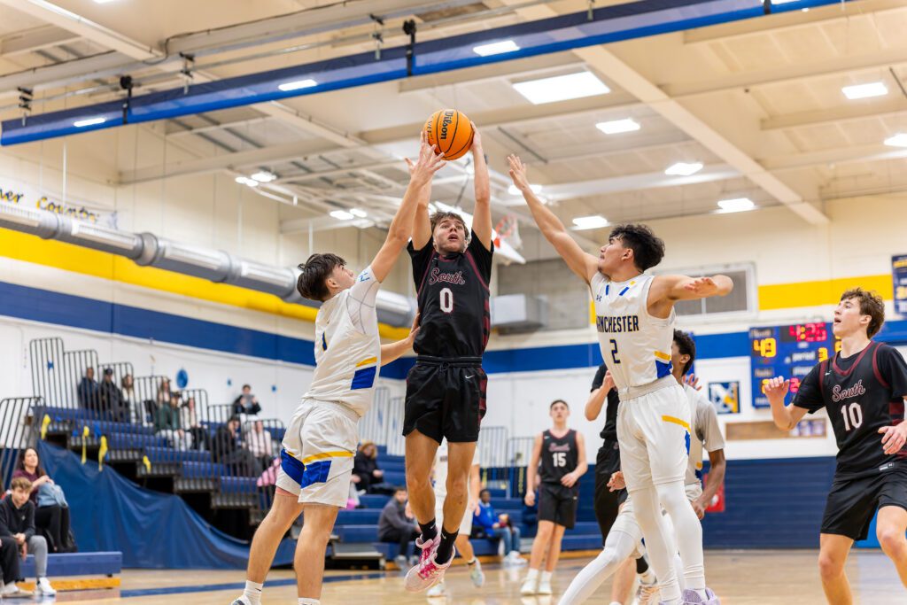 Toms River South senior Shane Gambarony takes off for a shot between Manchester sophomore Justin Roberts (left) and senior James Ruocchio. (Photo: Patrick Olivero) - Photos from 2025 Kevin Williams Christmas Classic Basketball Tournament